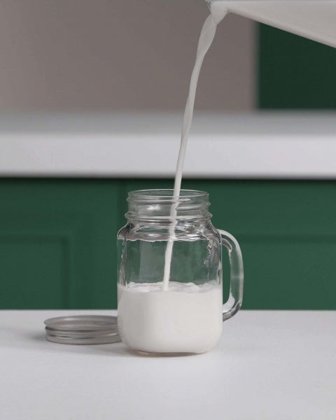 Mujer haciendo leche espumosa con batidora de mano mezclando leche