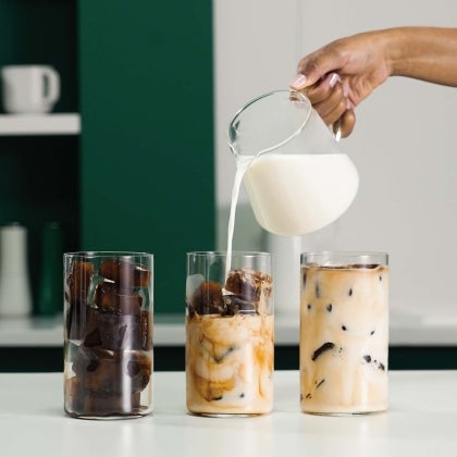 Milk is pouring into cup with coffee